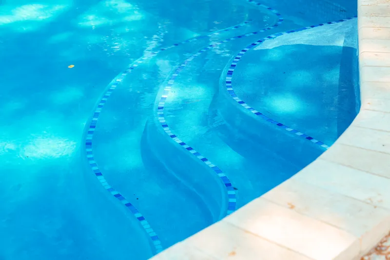 Curved entry steps seen through clear pool water in Morganville NJ