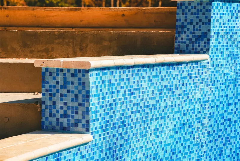 Close up of stone caps on a tiled pool wall in Morganville NJ